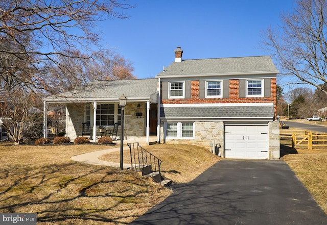 tri-level home featuring covered porch, a chimney, a garage, stone siding, and aphalt driveway