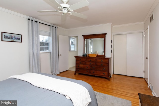 bedroom with a closet, visible vents, crown molding, and light wood-style floors