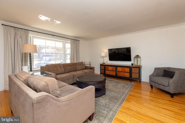 living room with crown molding, baseboards, and light wood-type flooring