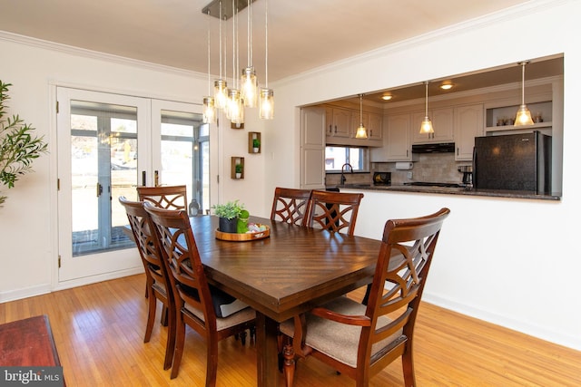 dining room with crown molding, french doors, light wood-type flooring, and baseboards