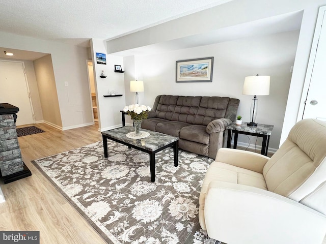 living area with a textured ceiling, baseboards, and wood finished floors