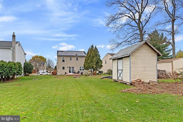rear view of property featuring a storage shed, a yard, and an outdoor structure