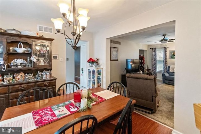 dining space featuring ceiling fan with notable chandelier, wood finished floors, and visible vents