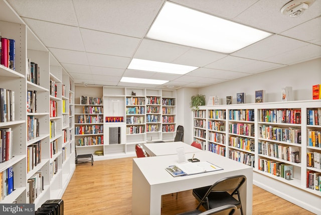 office featuring a paneled ceiling, bookshelves, and wood finished floors