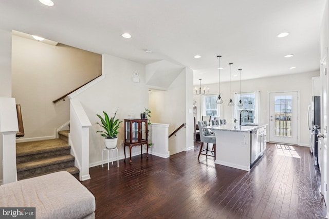 kitchen with light stone counters, dark wood-type flooring, a sink, white cabinets, and dishwasher