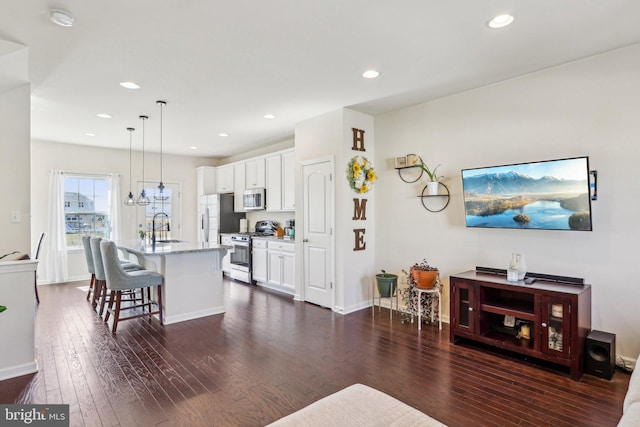 living area with baseboards, dark wood-style flooring, and recessed lighting