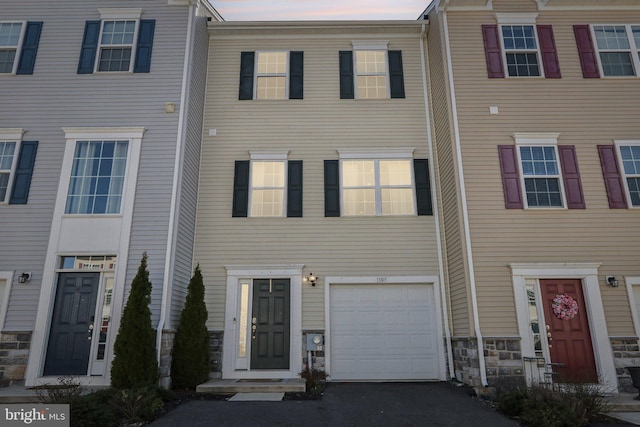 townhome / multi-family property with stone siding and an attached garage