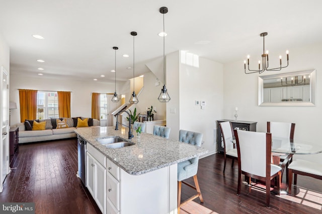 kitchen featuring a kitchen island with sink, dark wood-type flooring, a sink, white cabinets, and stainless steel dishwasher