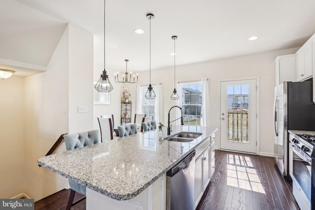 kitchen featuring dark wood-style floors, a breakfast bar, stainless steel appliances, white cabinetry, and a sink