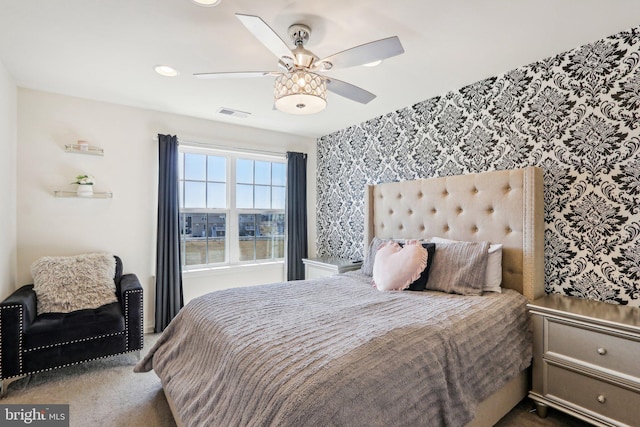 bedroom featuring wallpapered walls, visible vents, a ceiling fan, and carpet flooring