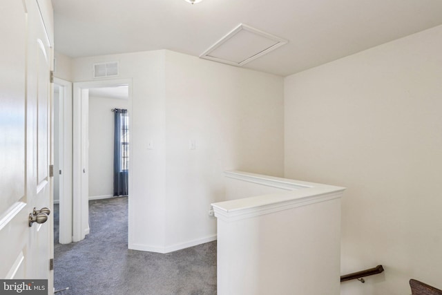 hallway with visible vents, baseboards, an upstairs landing, carpet, and attic access