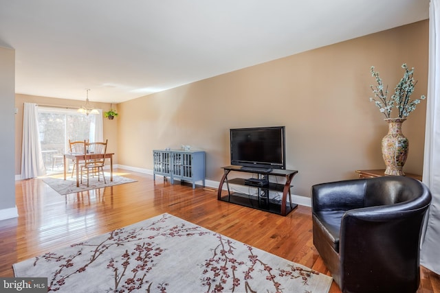 living room with baseboards, a chandelier, and wood finished floors