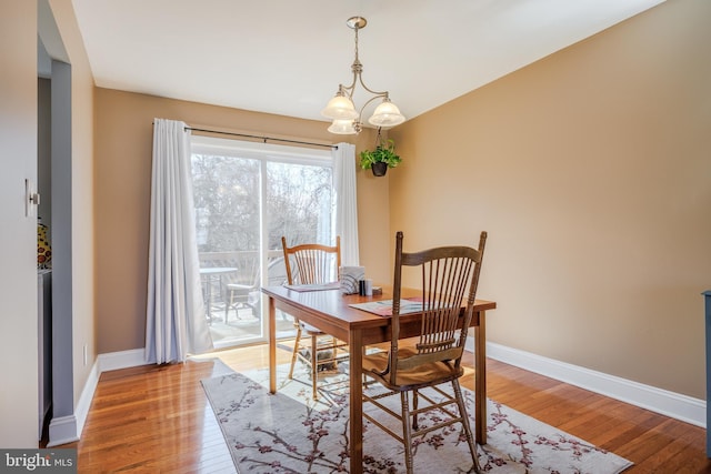 dining area with light wood-style floors, a chandelier, and baseboards