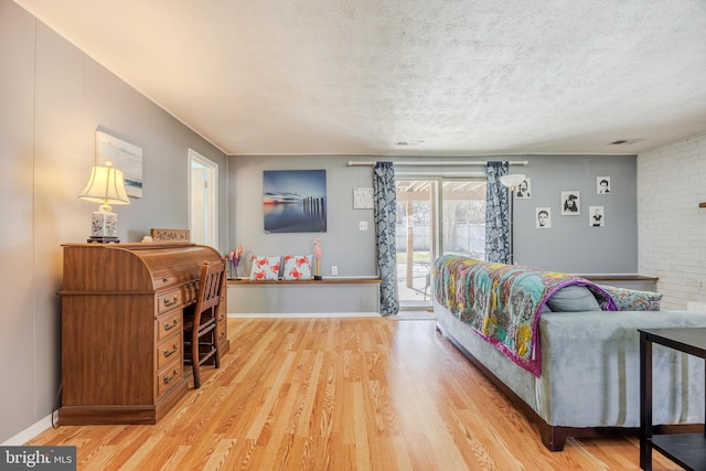 bedroom with access to outside, a textured ceiling, and wood finished floors