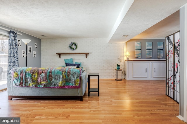 living area with brick wall, a textured ceiling, and wood finished floors