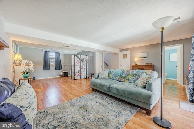 living room featuring a textured ceiling, stairs, wood finished floors, and visible vents