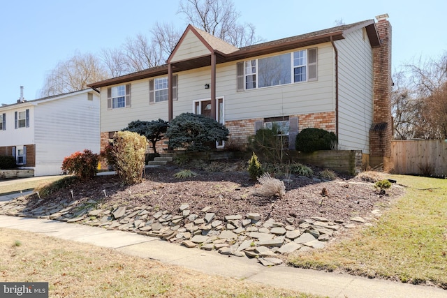 split foyer home with brick siding, fence, and a chimney