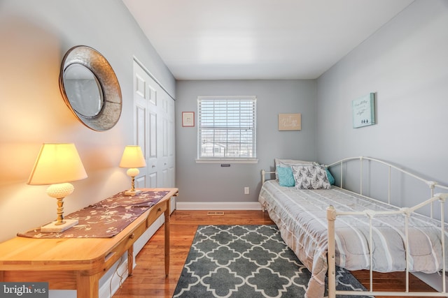 bedroom with a closet, wood finished floors, and baseboards