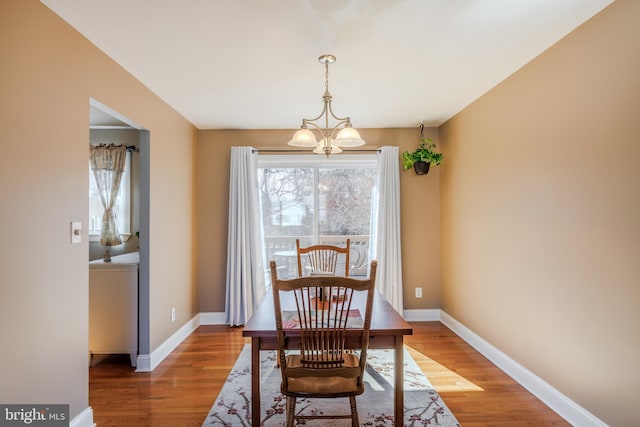 dining space featuring baseboards, wood finished floors, and an inviting chandelier