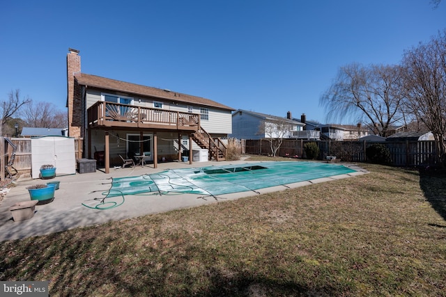 back of property featuring a fenced backyard, stairway, a storage unit, a wooden deck, and a patio area