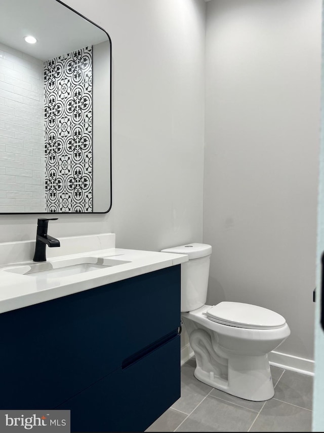 bathroom with tile patterned flooring, vanity, toilet, and baseboards