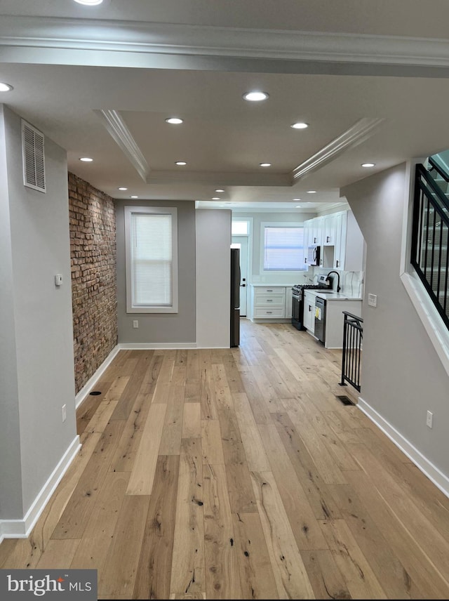 unfurnished living room with light wood-type flooring, a raised ceiling, visible vents, and recessed lighting