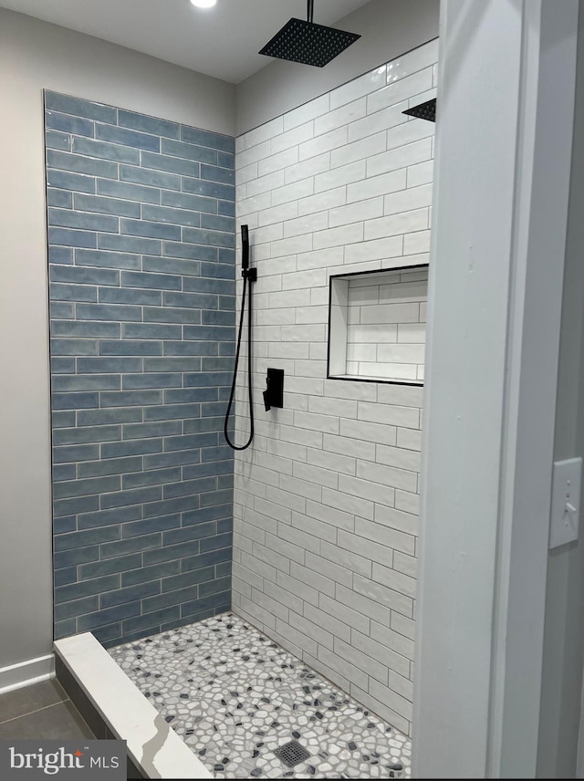 bathroom with a tile shower and tile patterned floors