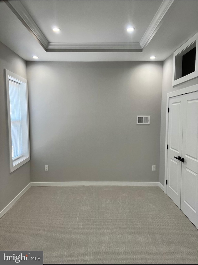 unfurnished room featuring baseboards, visible vents, a tray ceiling, and ornamental molding