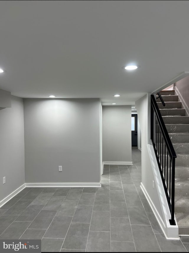 finished below grade area featuring tile patterned floors, baseboards, stairway, and recessed lighting