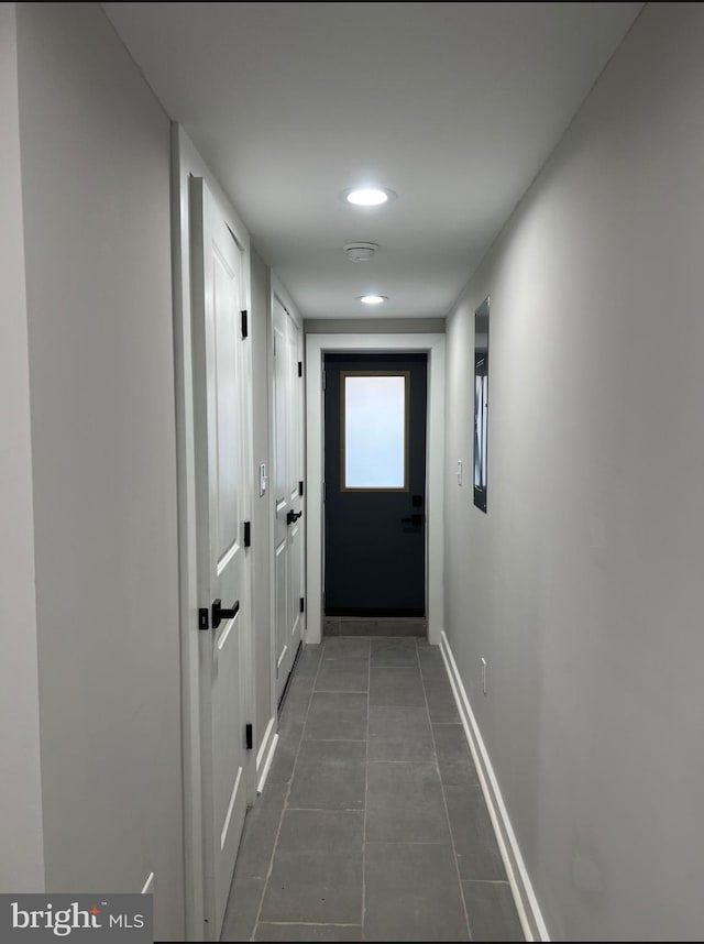 hallway with dark tile patterned flooring and baseboards