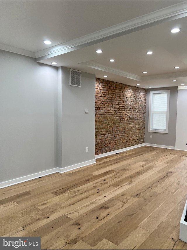 basement with ornamental molding, visible vents, and hardwood / wood-style floors