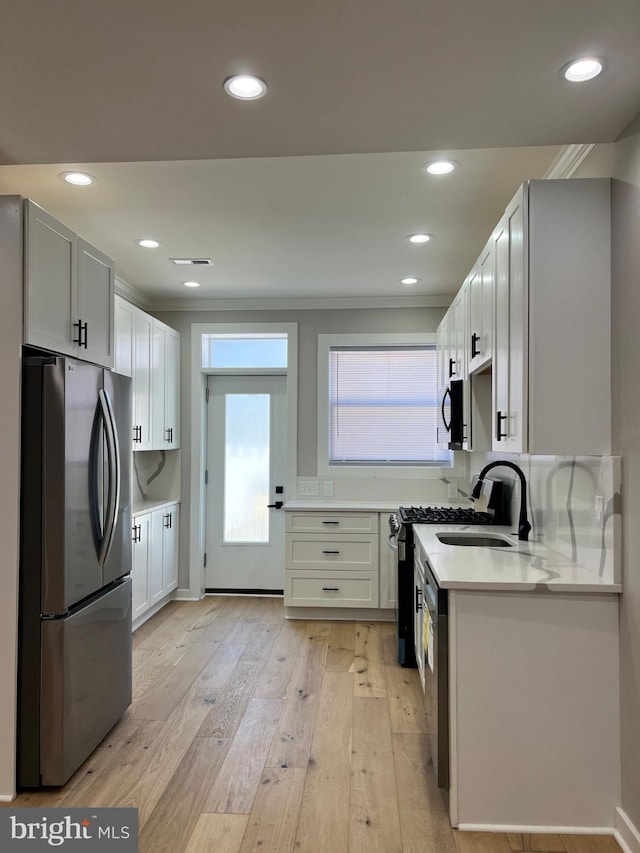 kitchen featuring appliances with stainless steel finishes, light countertops, light wood-type flooring, a sink, and recessed lighting