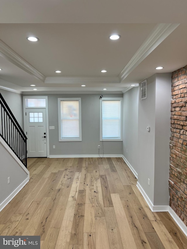 interior space featuring light wood-style floors, a tray ceiling, and crown molding