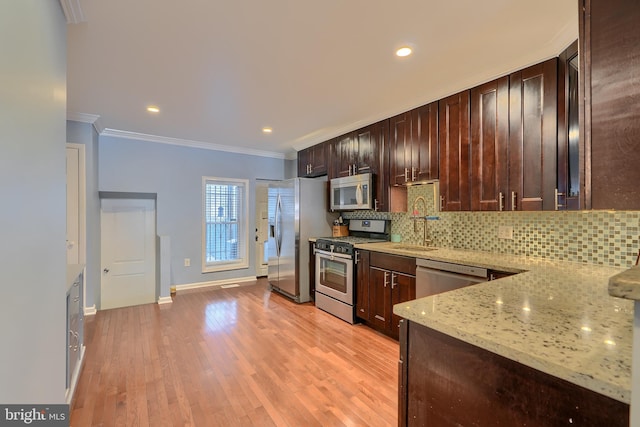 kitchen with ornamental molding, a sink, light stone counters, backsplash, and appliances with stainless steel finishes