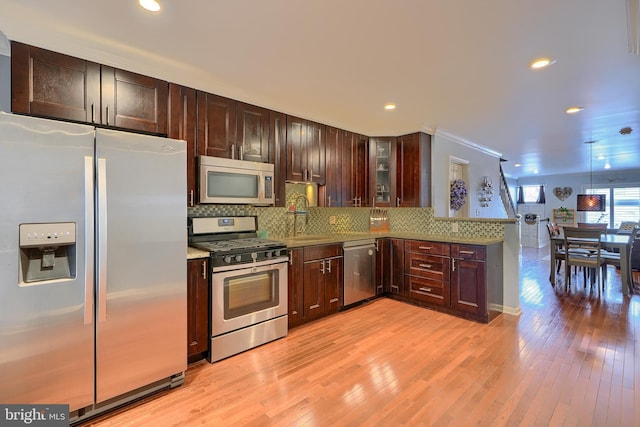 kitchen featuring stainless steel appliances, decorative backsplash, dark brown cabinetry, glass insert cabinets, and light wood-type flooring