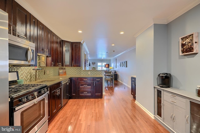 kitchen with a sink, decorative backsplash, stainless steel appliances, crown molding, and light wood-type flooring