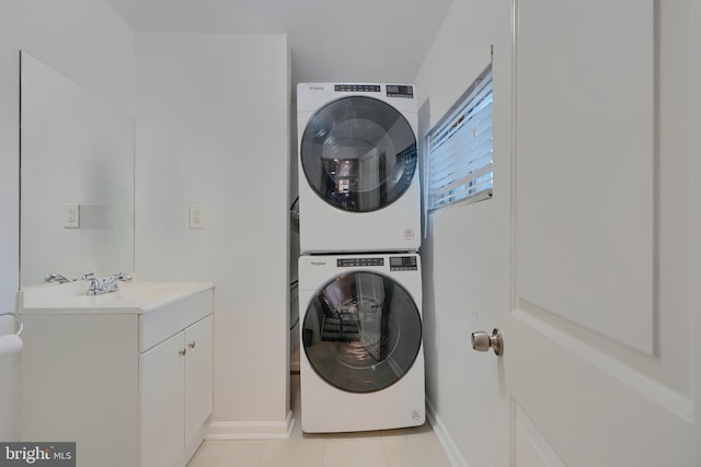 clothes washing area with light tile patterned floors, baseboards, laundry area, a sink, and stacked washer and clothes dryer