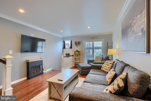 living room with wood finished floors, baseboards, recessed lighting, a glass covered fireplace, and crown molding