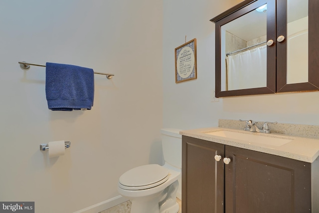 bathroom with toilet, vanity, and baseboards