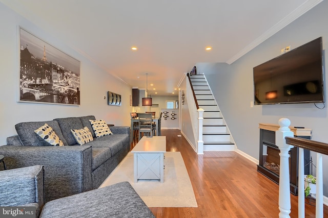 living room featuring crown molding, baseboards, stairs, recessed lighting, and wood finished floors