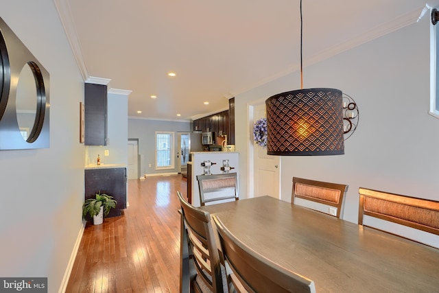 dining area with recessed lighting, baseboards, wood-type flooring, and ornamental molding