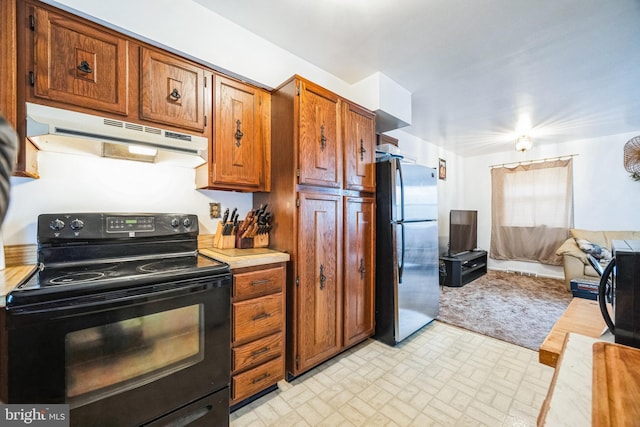 kitchen with under cabinet range hood, open floor plan, black range with electric cooktop, freestanding refrigerator, and light countertops