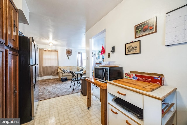 kitchen featuring open floor plan, brick patterned floor, light countertops, and freestanding refrigerator