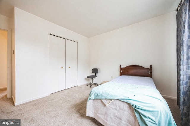 carpeted bedroom featuring baseboards and a closet