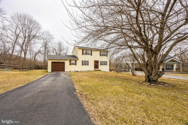 colonial house with aphalt driveway, a front yard, an attached garage, and fence