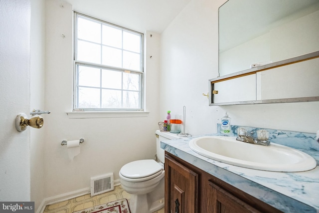 half bath featuring visible vents, toilet, vanity, and baseboards