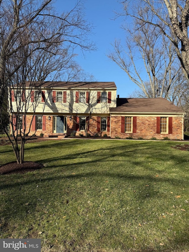 colonial inspired home featuring brick siding and a front yard