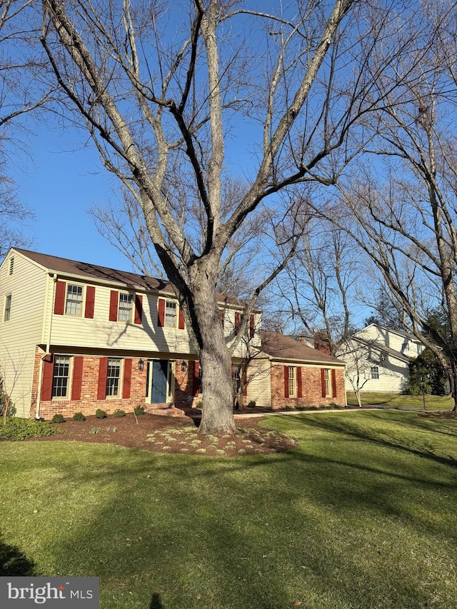 colonial inspired home featuring a front lawn and brick siding