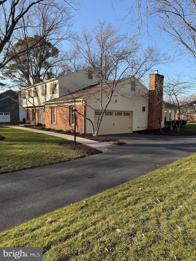 view of front of home with aphalt driveway, a chimney, and a front lawn