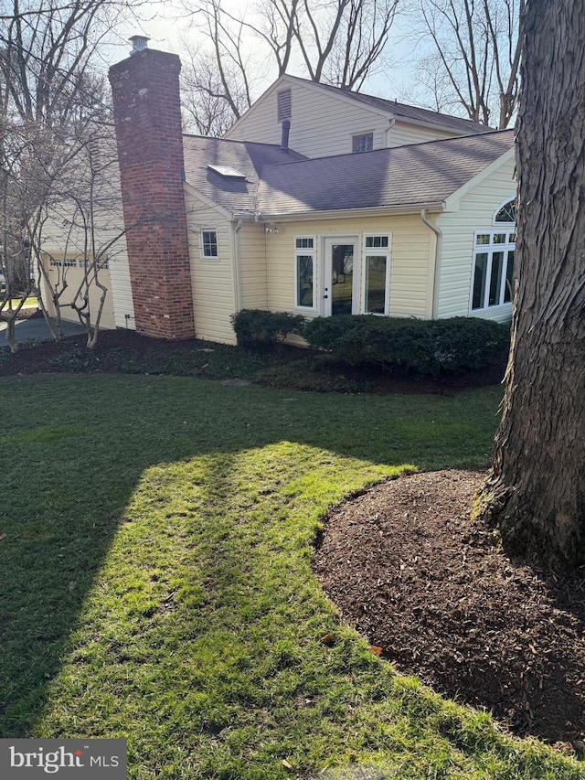 exterior space with a chimney, a front lawn, and roof with shingles